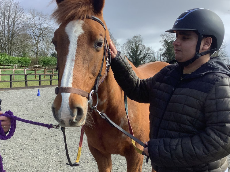 Young man with a horse at a riding school