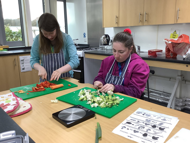 Two young women working in a college kitchen